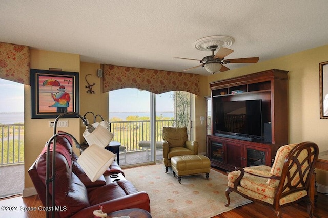 living room featuring a textured ceiling, hardwood / wood-style floors, a healthy amount of sunlight, and ceiling fan