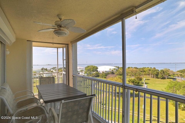 sunroom / solarium with a water view and ceiling fan