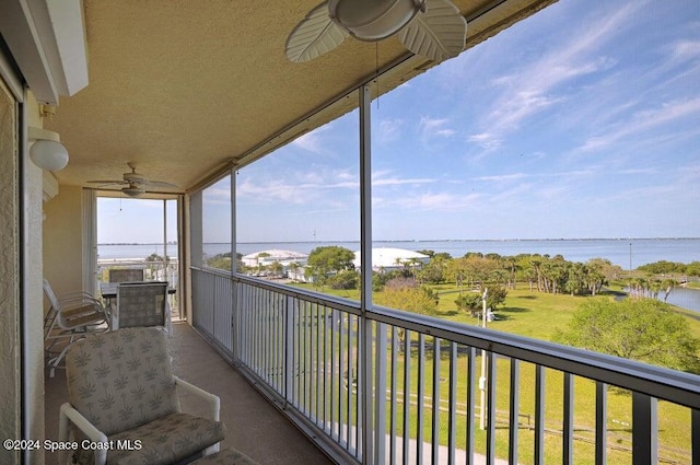 balcony with ceiling fan and a water view