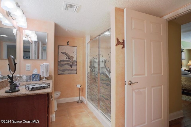 bathroom featuring toilet, tile patterned flooring, a textured ceiling, an enclosed shower, and vanity