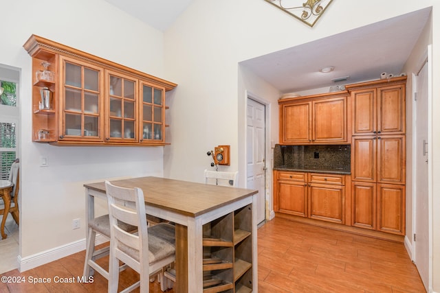 kitchen with dark stone counters, light wood-type flooring, and backsplash