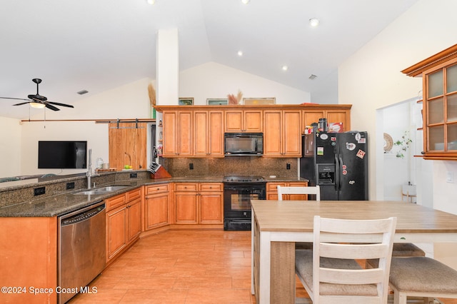 kitchen featuring kitchen peninsula, black appliances, a barn door, sink, and backsplash