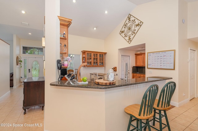 kitchen featuring a kitchen bar, kitchen peninsula, and dark stone countertops