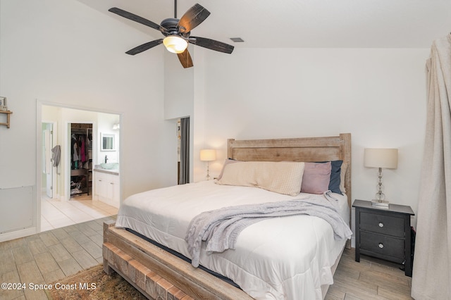 bedroom featuring high vaulted ceiling, ceiling fan, a closet, light hardwood / wood-style flooring, and a walk in closet