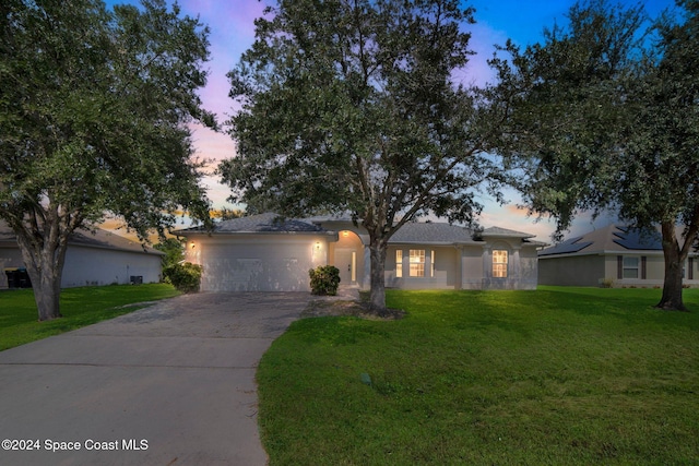 single story home featuring a garage and a lawn