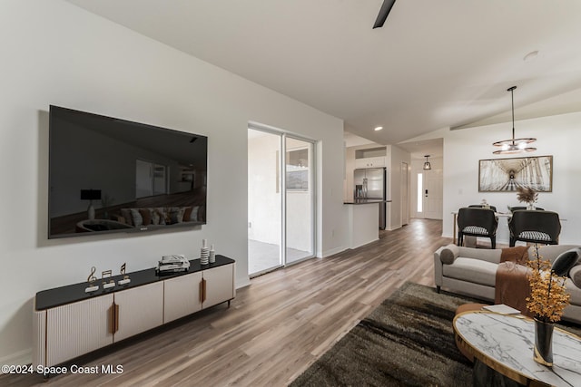 living room featuring a notable chandelier, wood-type flooring, and lofted ceiling