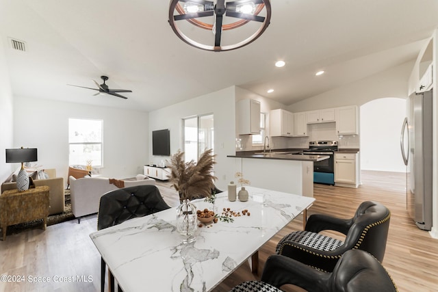 dining room featuring light hardwood / wood-style floors, lofted ceiling, sink, and ceiling fan