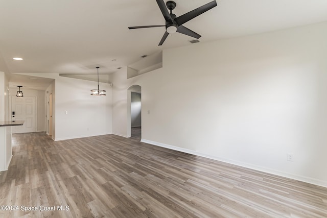 unfurnished living room featuring light hardwood / wood-style floors, vaulted ceiling, and ceiling fan