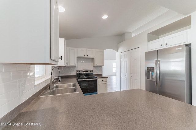 kitchen with lofted ceiling, backsplash, appliances with stainless steel finishes, white cabinetry, and sink