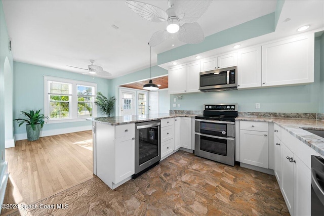 kitchen featuring wine cooler, pendant lighting, kitchen peninsula, appliances with stainless steel finishes, and white cabinets