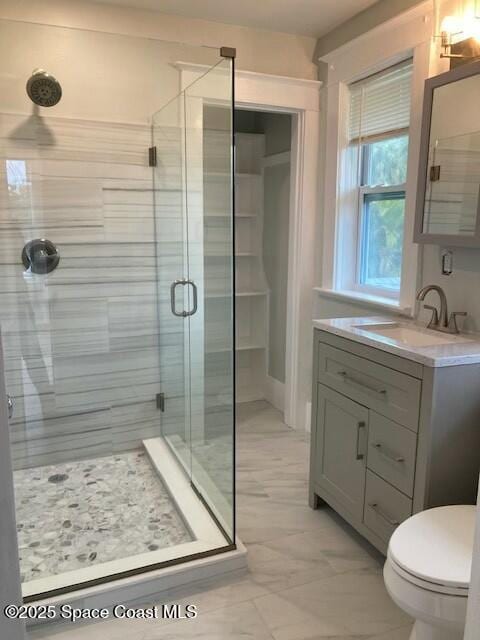 bathroom with toilet, vanity, and a shower with door