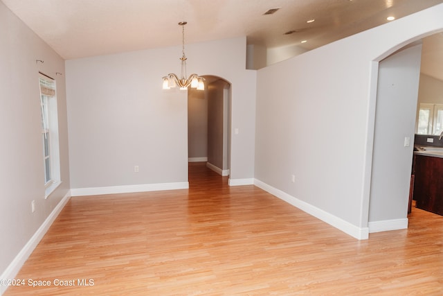 unfurnished room with a notable chandelier and light hardwood / wood-style flooring