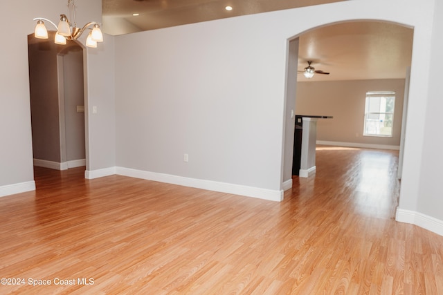 spare room featuring light wood-type flooring and ceiling fan with notable chandelier