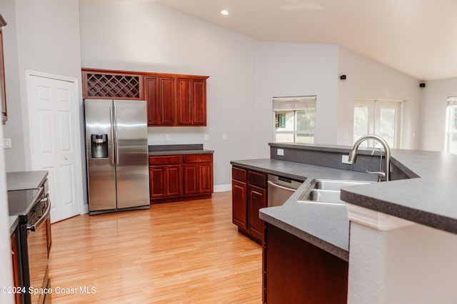 kitchen featuring appliances with stainless steel finishes, sink, high vaulted ceiling, and light wood-type flooring