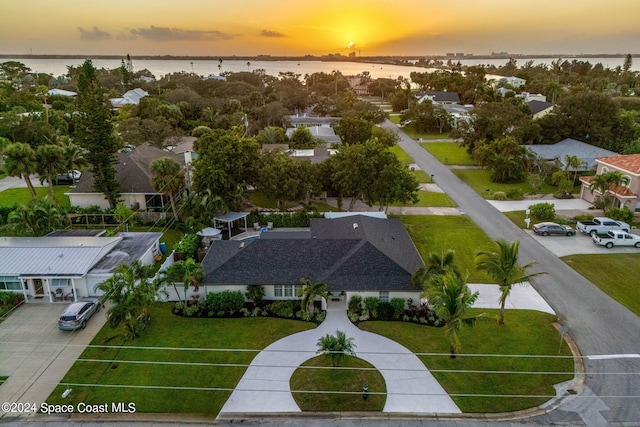 aerial view at dusk featuring a water view