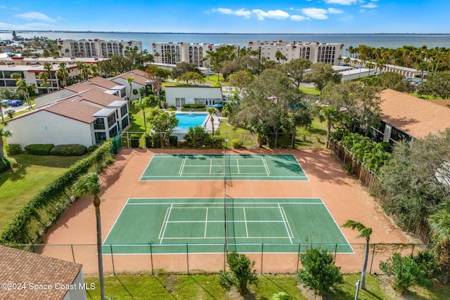 view of tennis court featuring a fenced in pool and a water view