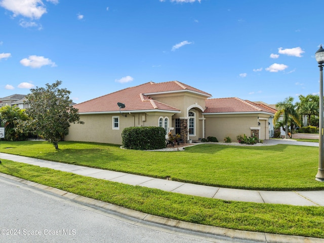 mediterranean / spanish home with a front yard and a garage