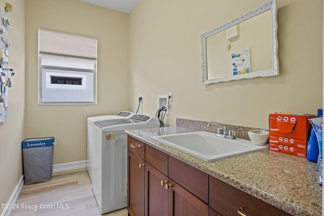 laundry room with cabinets, sink, light wood-type flooring, and washer and clothes dryer