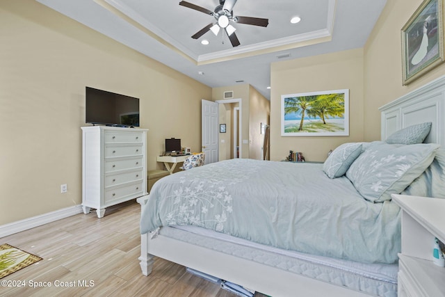 bedroom with a raised ceiling, crown molding, light wood-type flooring, and ceiling fan