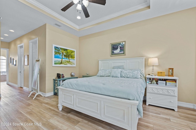 bedroom featuring ceiling fan, a tray ceiling, ornamental molding, and light hardwood / wood-style flooring