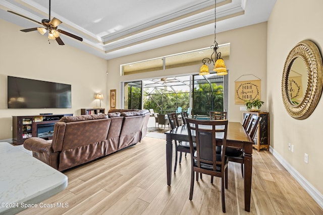 dining space with light hardwood / wood-style floors, ornamental molding, a tray ceiling, and ceiling fan