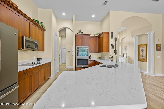 kitchen with decorative columns, light hardwood / wood-style flooring, appliances with stainless steel finishes, and sink