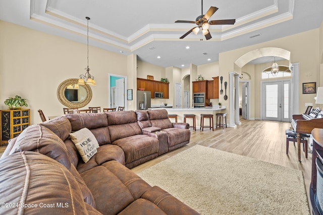 living room with crown molding, a tray ceiling, light wood-type flooring, and ceiling fan