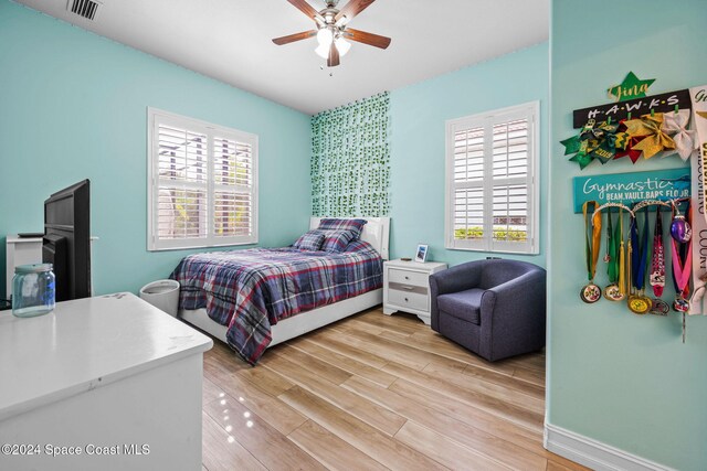 bedroom with multiple windows, light hardwood / wood-style floors, and ceiling fan