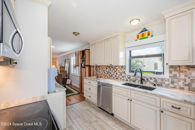 kitchen with light stone countertops, appliances with stainless steel finishes, light hardwood / wood-style floors, and sink