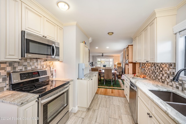 kitchen with cream cabinetry, decorative backsplash, light hardwood / wood-style floors, and appliances with stainless steel finishes