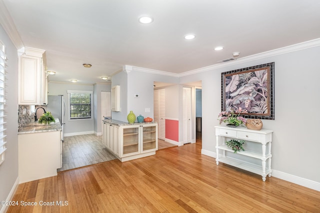 interior space with white cabinetry, crown molding, and light hardwood / wood-style flooring