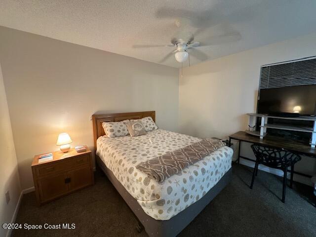 bedroom with ceiling fan, a textured ceiling, and dark colored carpet