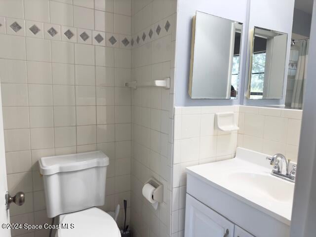 bathroom featuring vanity, toilet, and tile walls