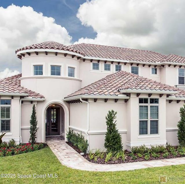 mediterranean / spanish house with a tile roof, stucco siding, and a front lawn