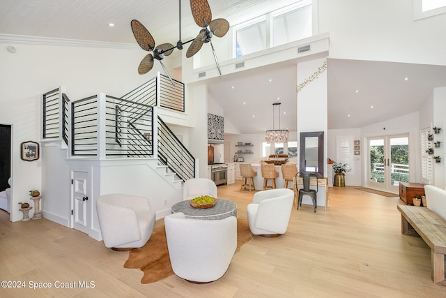 living room with ceiling fan, french doors, a towering ceiling, and light wood-type flooring