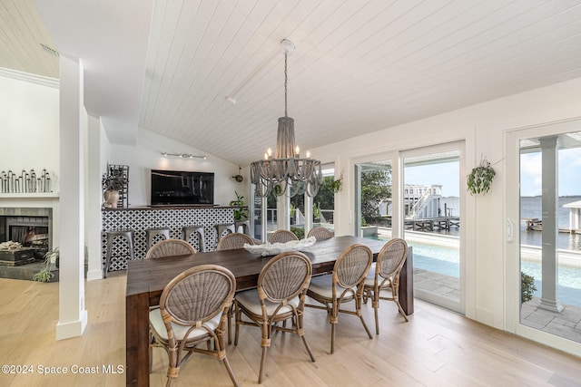 dining room featuring light wood-type flooring, wood ceiling, a tile fireplace, an inviting chandelier, and lofted ceiling