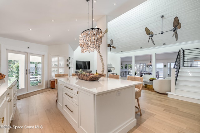 kitchen featuring a center island, pendant lighting, a kitchen bar, white cabinets, and ceiling fan with notable chandelier