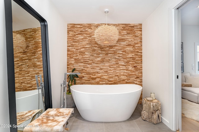 bathroom with a washtub, tile patterned flooring, and a chandelier