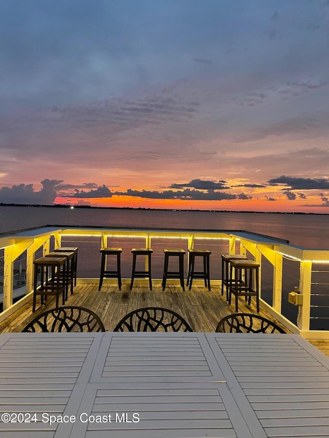 deck at dusk featuring a water view