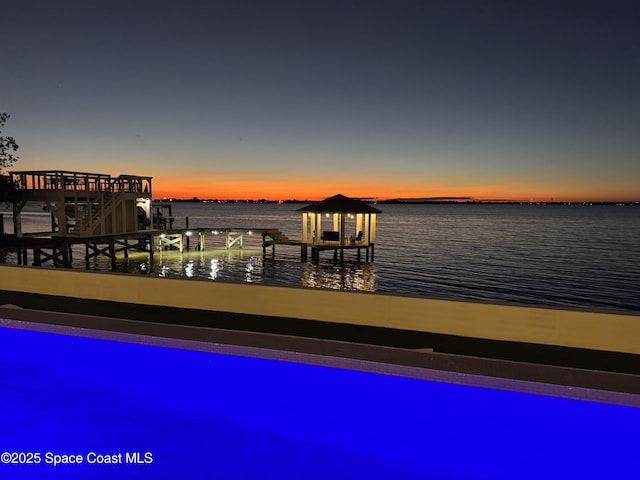 pool at dusk featuring a water view