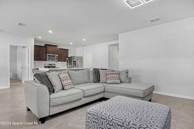 living room with a textured ceiling and light tile patterned flooring