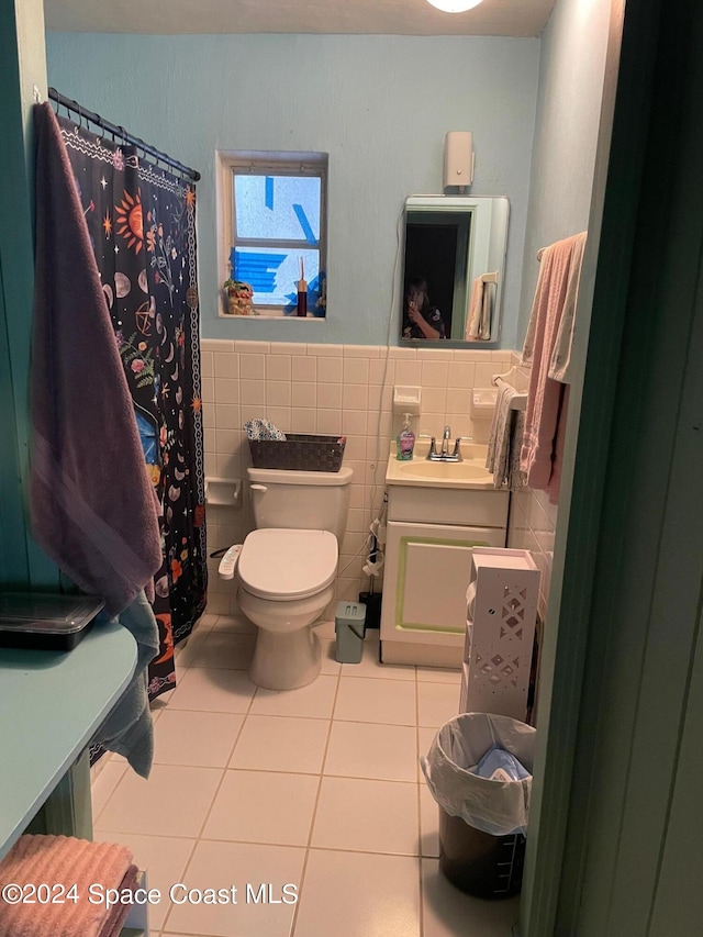 bathroom with tile walls, toilet, vanity, tile patterned floors, and a shower with shower curtain