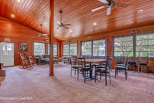 dining area with light carpet, wood ceiling, ceiling fan, high vaulted ceiling, and wooden walls