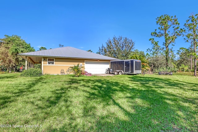 rear view of house featuring a garage and a lawn