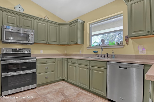 kitchen featuring lofted ceiling, light tile patterned flooring, stainless steel appliances, sink, and green cabinets