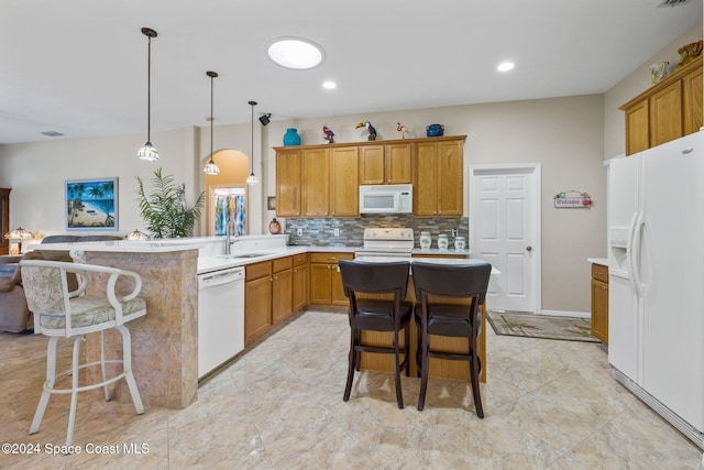 kitchen featuring a breakfast bar, white appliances, hanging light fixtures, and sink