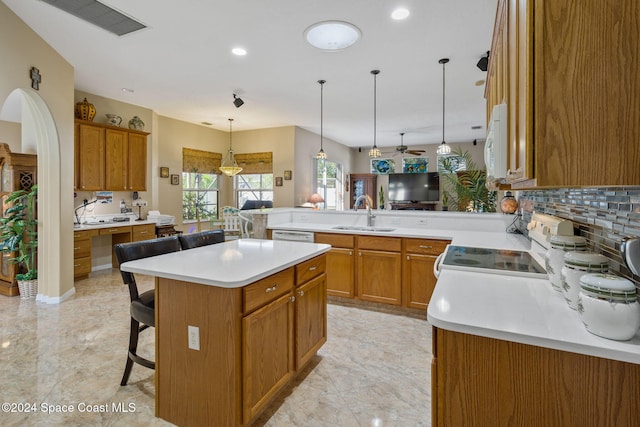 kitchen featuring ceiling fan, sink, kitchen peninsula, a breakfast bar, and a kitchen island