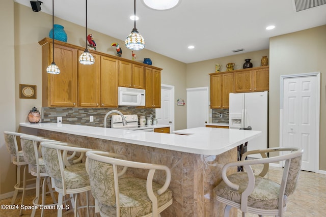 kitchen with a kitchen breakfast bar, tasteful backsplash, decorative light fixtures, and white appliances