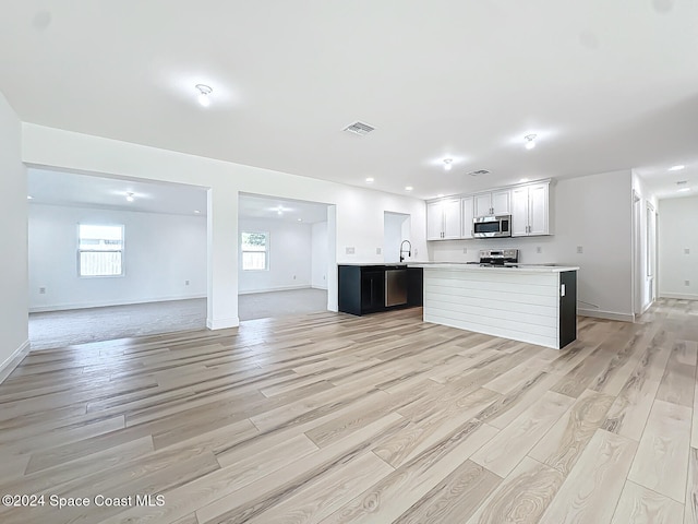 kitchen with appliances with stainless steel finishes, white cabinetry, a center island, and light wood-type flooring