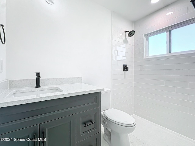 bathroom featuring vanity, toilet, and tiled shower